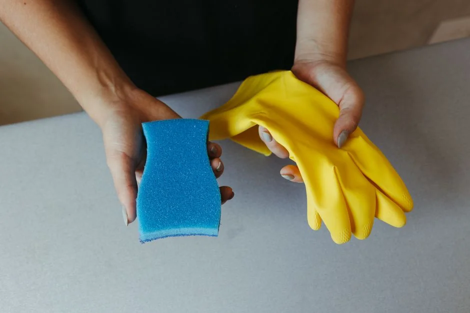 services-04 a-woman-in-a-green-shirt-and-black-gloves-vacuuming-a-gray-ottoman-5txz228u4eo